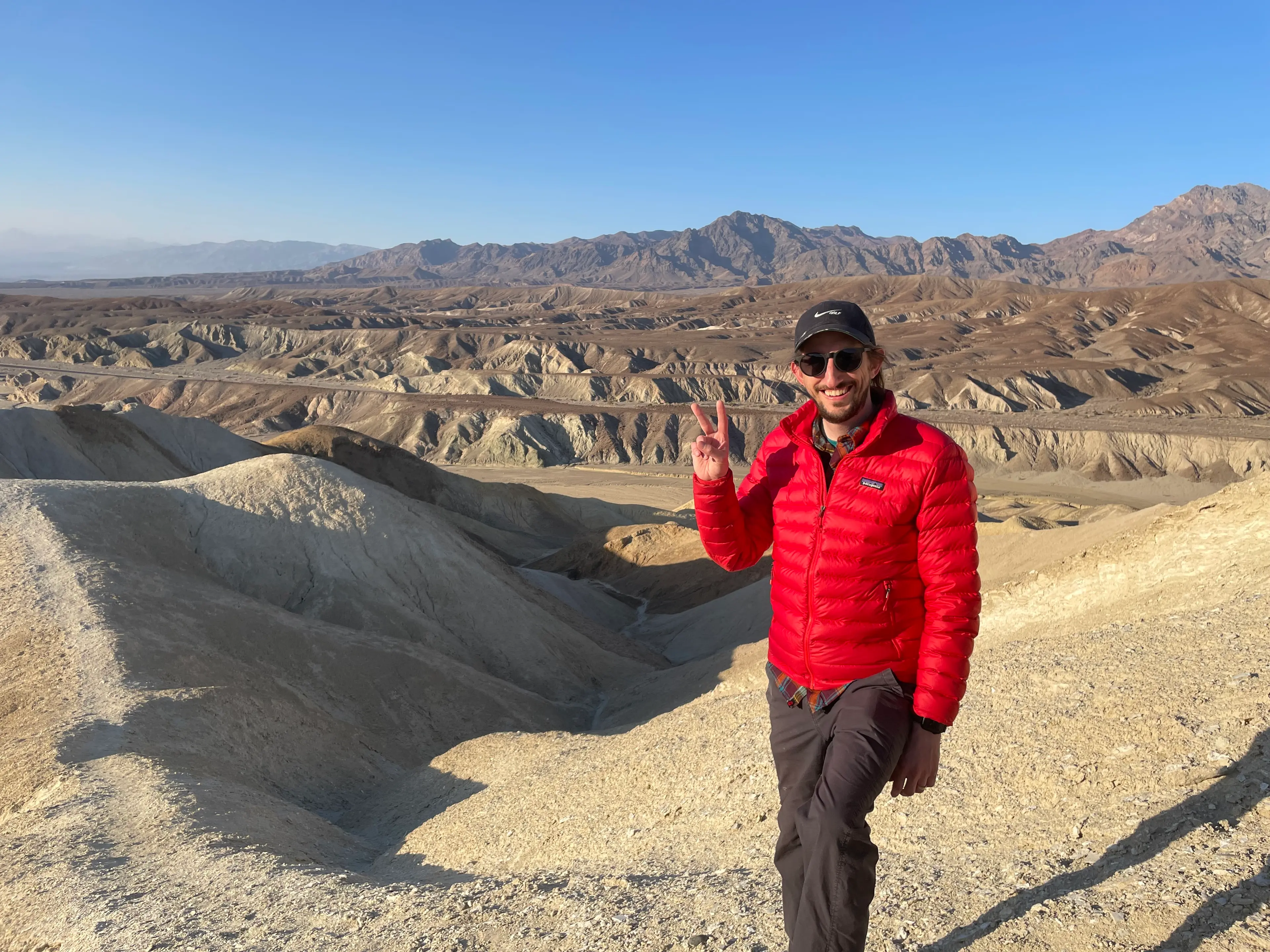 Outside the City's Corey Swift flashes a peace sign above the eroded badlands of Death Valley, with mountains behind